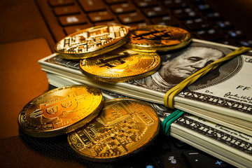 Gold coins cryptocurrency lie with packs of dollars on the laptop keyboard