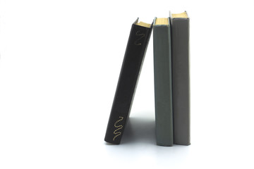 two gray and one brown old books standing on a white background close-up