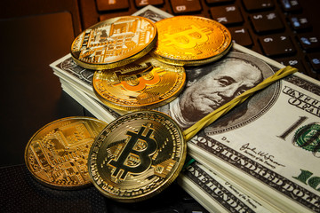 Gold coins cryptocurrency lie with packs of dollars on the laptop keyboard
