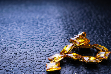 Beautiful and fashionable jewelry and accessories for women. Yellow, orange stones with square stones on dark and wood textured background. Mustard bright rhinestones on a Gold metal base. Interesting