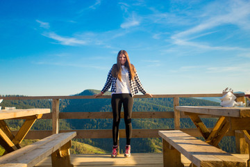 Young woman with long hair have rest in open air cafe on top of mountains and enjoy view