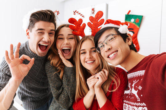 Group of european and asian friends celebrating New Year, and taking selfie photo together