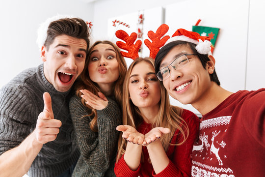 Group of cheerful multiethnic people celebrating New Year, and taking selfie photo together