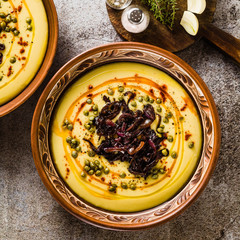 Authentic Greek Fava recipe, Middle Eastern yellow lentil soup with caramelized onions, paprika and capers. vegan healthy food in clay pots on the stone table