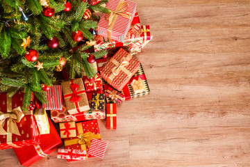 Top view composition of Christmas tree branches with stack of different presents in colorful...