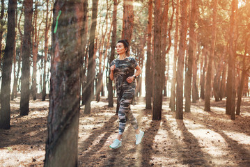 Young fitness woman running at morning. Woman wearing military-colored clothing and smart watch