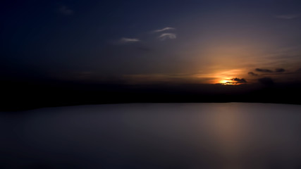 Landscape shot of sun setting with some clouds in the ancient lake.