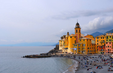 Fototapeta na wymiar colorful buildings, church and architecture with crowd of people on the beach in picturesque village Camogli in liguria, nothern italy