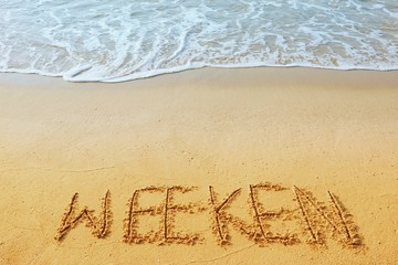 The word concept, WEEKEN handwriting on sand beach.
