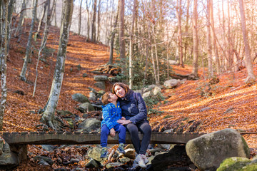 Fototapeta na wymiar Mother and son sitting on a bridge in autumn