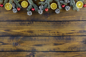 Christmas decorations, pine cones, orange fruit and red balls on a brown wooden table. Top view, copy space.