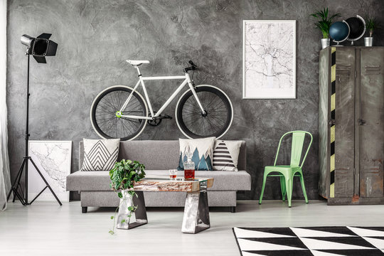 Dark industrial living room with grey couch and white bike