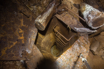 Underground abandoned gold iron ore mine shaft tunnel gallery passage wtih vertical round ladder stairs