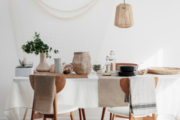 Natural dining room with linen napkins, white tablecloth and wicker lamp