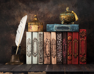 Vintage books on a shelf, ancient caskets, manuscript and antiquarian inkwell with a feather. Retro still life - obrazy, fototapety, plakaty