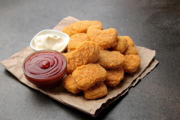 chicken nuggets with white and red sauce on a brown background. fast food