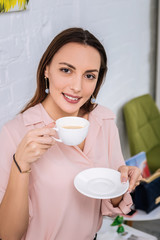 Pleasant fashionable woman drinking some coffee waiting for nail artist