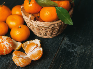 Tangerines in a wooden basket on a dark wooden table