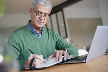  Modern senior man working on laptop at home