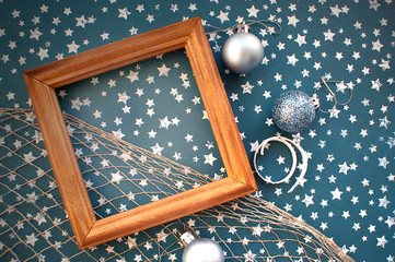 Wooden frame of gold color on a paper background with stars. Christmas decorations - silver balls and curls. Background for congratulations on Christmas and New Year. Photo album page template.