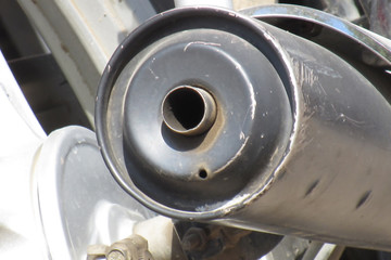 Close up of black and white colored steel and plastic silencer of typical common Indian bike on the roads.