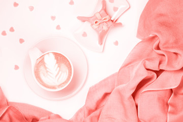 Coffee with pink scarf. Valentines concept. White background. Light, modern style. Gift style cake and heart shape sprikles.  . Living coral theme - color of the year 2019