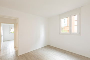 Empty room with white walls, open door and window with a view
