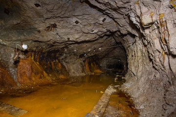 Underground abandoned gold iron ore mine shaft tunnel gallery passage wtih yellow water