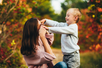 Mom and son hug and laugh in the autumn park. Space for text.