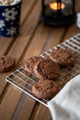Chocolate cookies at metal grill, with napkin and cup near on wood background