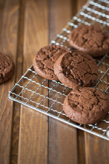 Chocolate cookies at metal grill on wood background