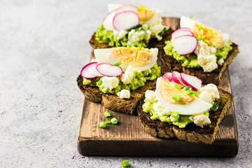 Avocado radish eggs bruschetta on cutting board. Selective fcous, space for text.