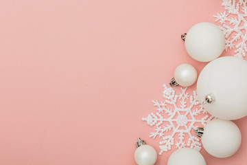 Festive winter composition. White christmas balls and snowflakes on a pastel pink background