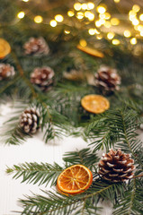 Christmas composition. Spruce branches with cones and orange on a white background. Gold garland