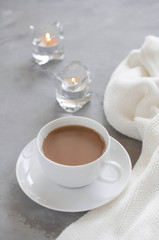 Cup of cocoa on a table, candles and knited blanket.