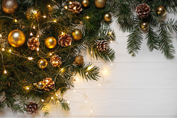 Christmas composition. Spruce branches with cones and Christmas toys of gold color on a white background. Gold garland. Made in flatlay style.