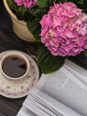 A cup of coffee, an open book and a bright pink hydrangea