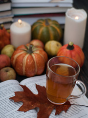 An open book, a cup of aromatic tea and a golden leaf