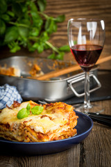 Piece of tasty hot lasagna with red wine.