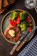 Grilled Beef steak with garlic butter and vegetables. Meat with grilled bell pepper, broccoli and onions.