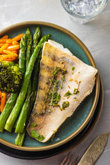 Pike perch fillet with asparagus, broccoli and carrots. Fried fish with stewed greens