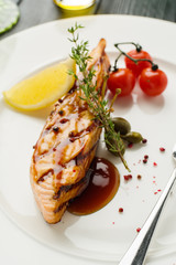 Grilled salmon steak with lemon and cherry tomatoes.