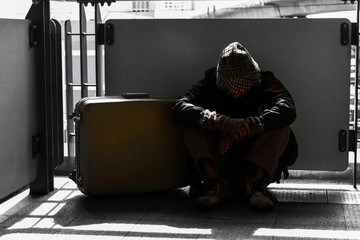 Homeless man  with baggage  sitting at train station in the city. Concept in dark tone.