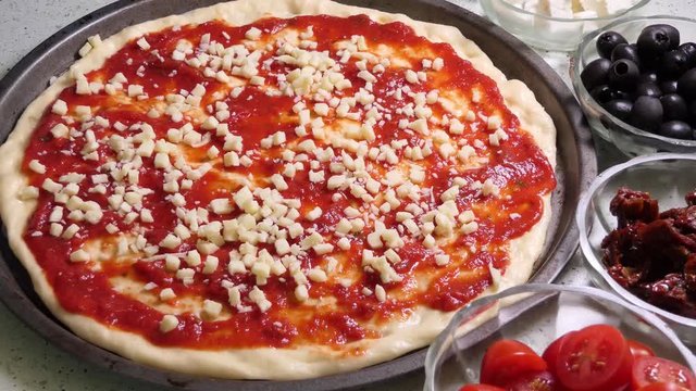 Preparing pizza toping. Laying fresh spinache leaves on pizza topping.