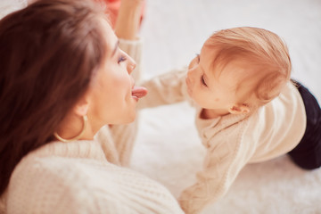 Winter holidays decorations. Warm colors. Family portrait. Adorable mom and daughter have fun posing before a rich Decorated Christmas tree in a cosy room