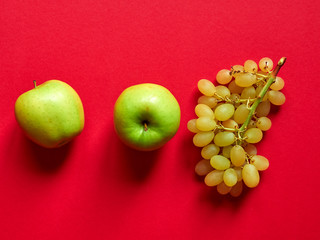 Above view of isolated set of a green apple with a bunch of sweet seedless grapes in studio with...