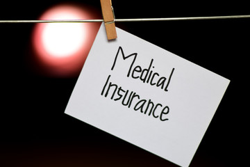 Medical Insurance handwriting on paper. Hanged with a clothes clips, medical and education concept. light blur background