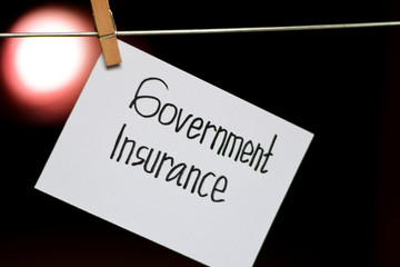 Government Insurance handwriting on paper. Hanged with a clothes clips, medical and education concept. light blur background