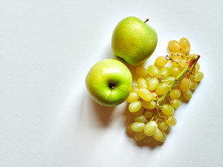 Above view of isolated set of a green apple with a bunch of sweet seedless grapes in studio with white background