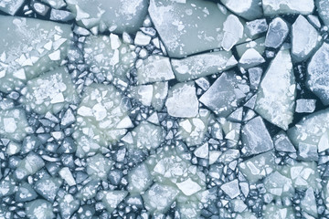 Abstract texture of broken white ice and dark water at winter. Spring is coming. Aerial view of the...